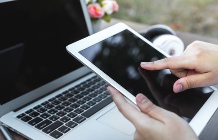 Finger am Tablet, Computer im Hintergrund